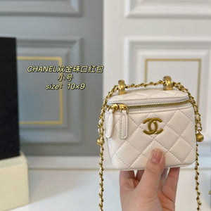 White quilted handbag with gold chain and hardware held by a hand against a neutral background