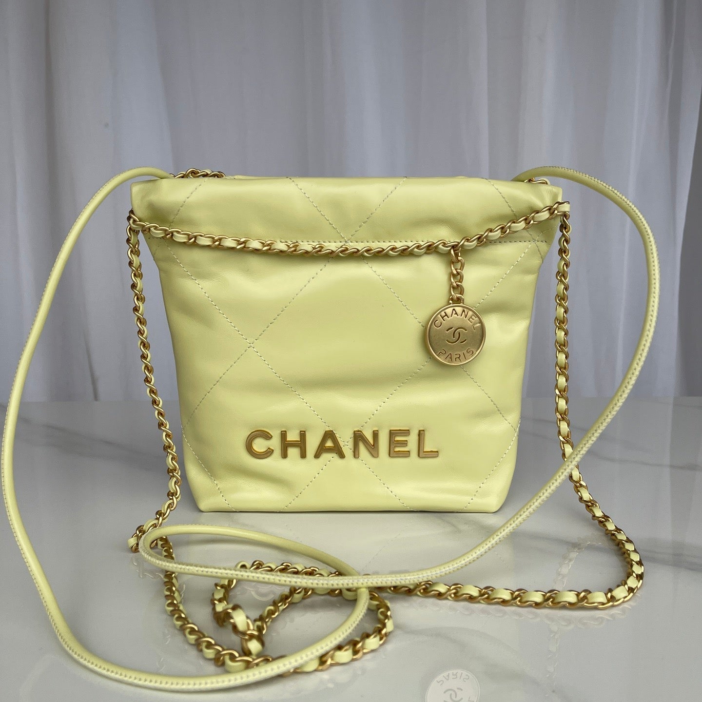 Chanel handbag with gold chain strap on a light gray background